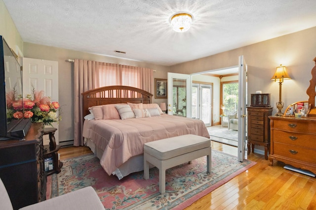 bedroom with french doors, a textured ceiling, hardwood / wood-style flooring, and baseboard heating