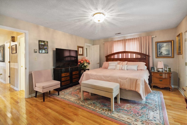 bedroom featuring a textured ceiling and light hardwood / wood-style floors