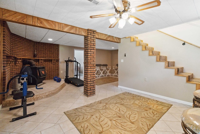 exercise room featuring decorative columns, a drop ceiling, ceiling fan, and light tile patterned floors