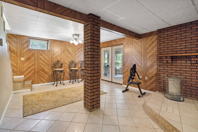 basement featuring wood walls, ceiling fan, a paneled ceiling, and tile patterned flooring