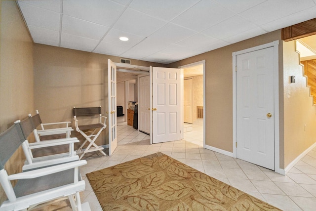 corridor with a drop ceiling and light tile patterned floors