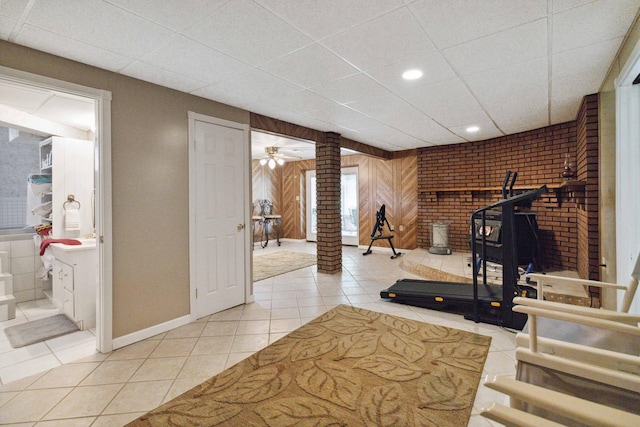 workout area featuring wood walls, ceiling fan, ornate columns, and tile patterned flooring