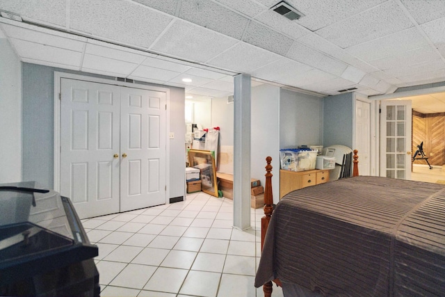 tiled bedroom featuring a closet and a drop ceiling