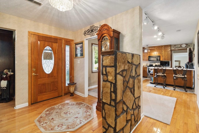 foyer featuring rail lighting, light hardwood / wood-style floors, a textured ceiling, and ceiling fan