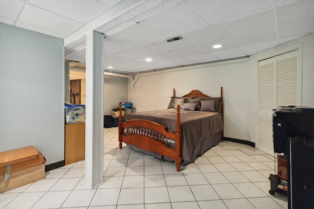 bedroom featuring a closet, a paneled ceiling, and light tile patterned flooring