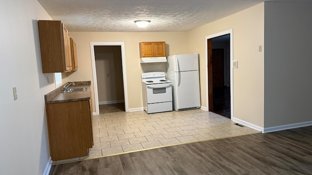 kitchen featuring white appliances, a textured ceiling, sink, and light wood-type flooring