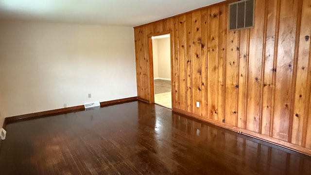 unfurnished room with wooden walls and dark hardwood / wood-style flooring