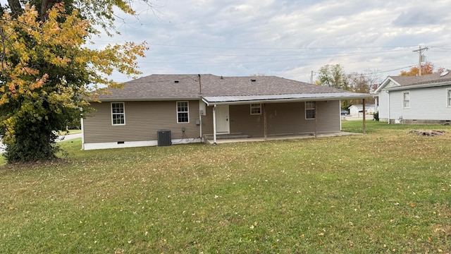 rear view of house with central AC and a lawn