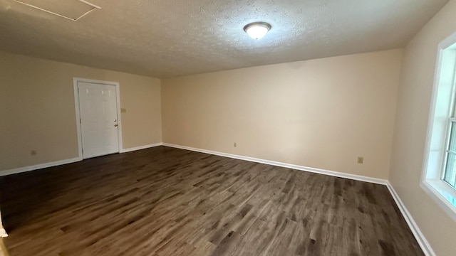 spare room with a textured ceiling and dark hardwood / wood-style floors