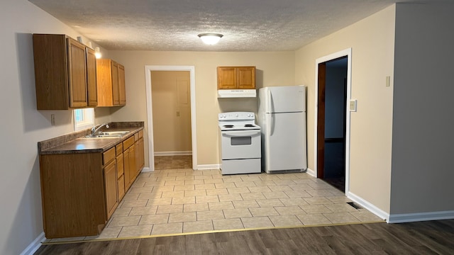 kitchen with light hardwood / wood-style flooring, a textured ceiling, sink, and white appliances