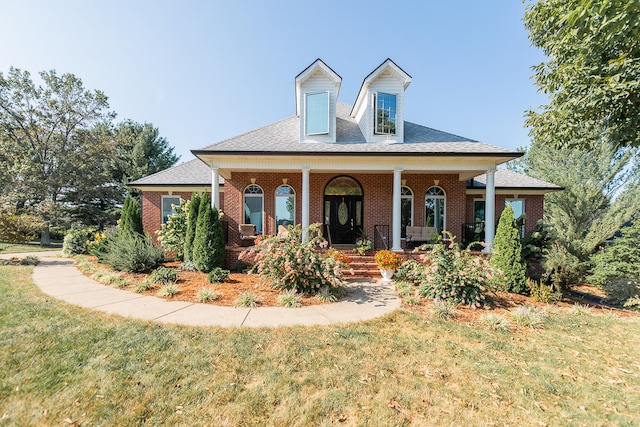 cape cod home featuring a porch and a front lawn