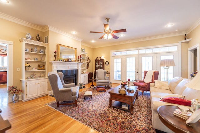 living room with crown molding, light hardwood / wood-style flooring, and ceiling fan