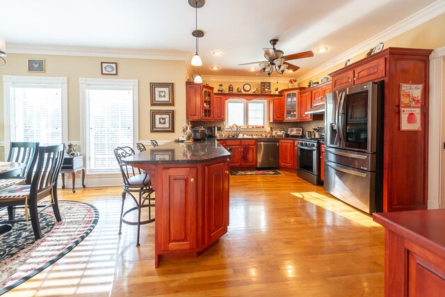 kitchen with decorative backsplash, a breakfast bar area, light hardwood / wood-style flooring, stainless steel appliances, and ornamental molding