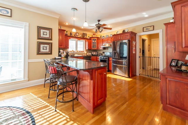 kitchen with ceiling fan, appliances with stainless steel finishes, light hardwood / wood-style flooring, ornamental molding, and decorative light fixtures