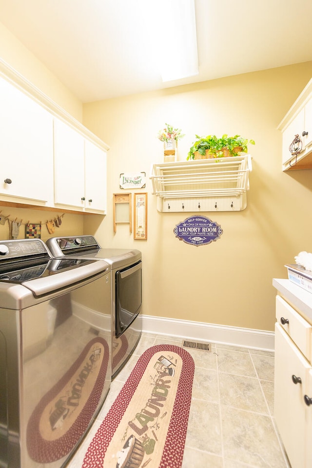 laundry room with light tile patterned floors, cabinets, and separate washer and dryer