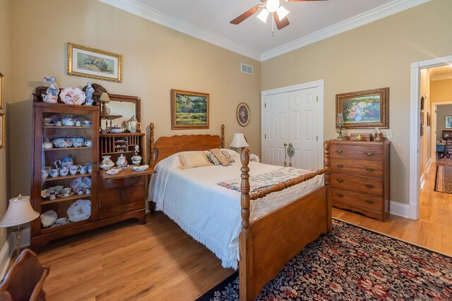 bedroom with light hardwood / wood-style floors, a closet, ornamental molding, and ceiling fan