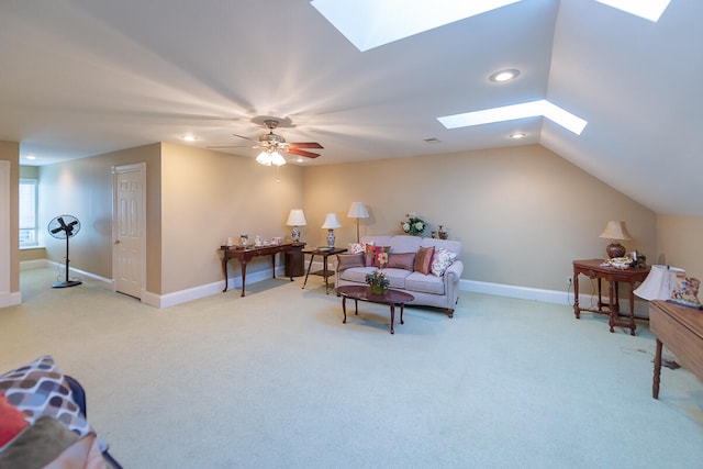 carpeted living room featuring vaulted ceiling with skylight and ceiling fan