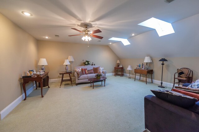 living room with vaulted ceiling with skylight, light carpet, and ceiling fan