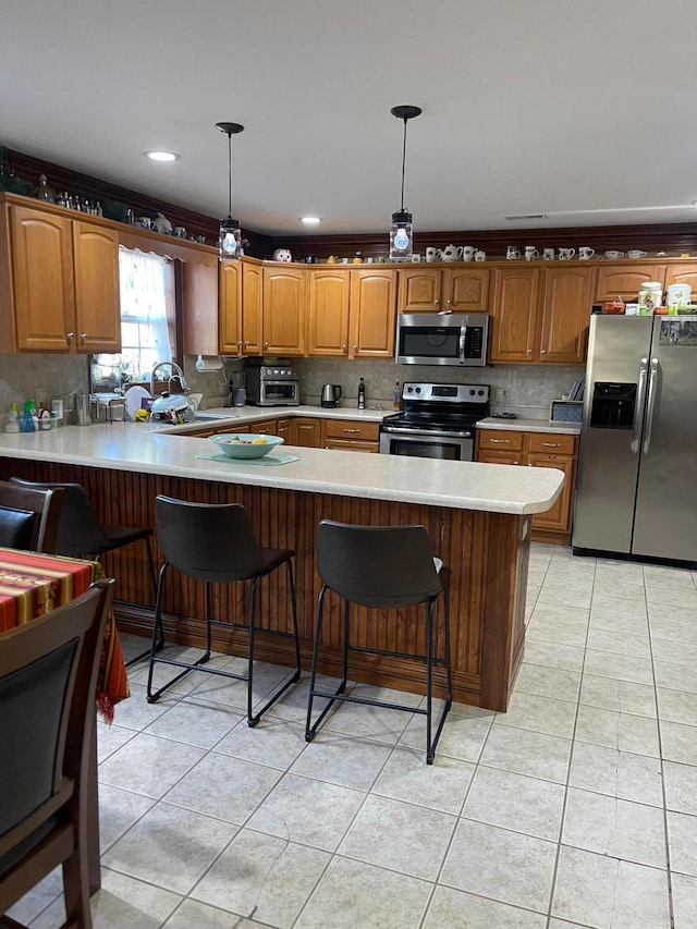 kitchen featuring appliances with stainless steel finishes, kitchen peninsula, a kitchen breakfast bar, hanging light fixtures, and light tile patterned floors