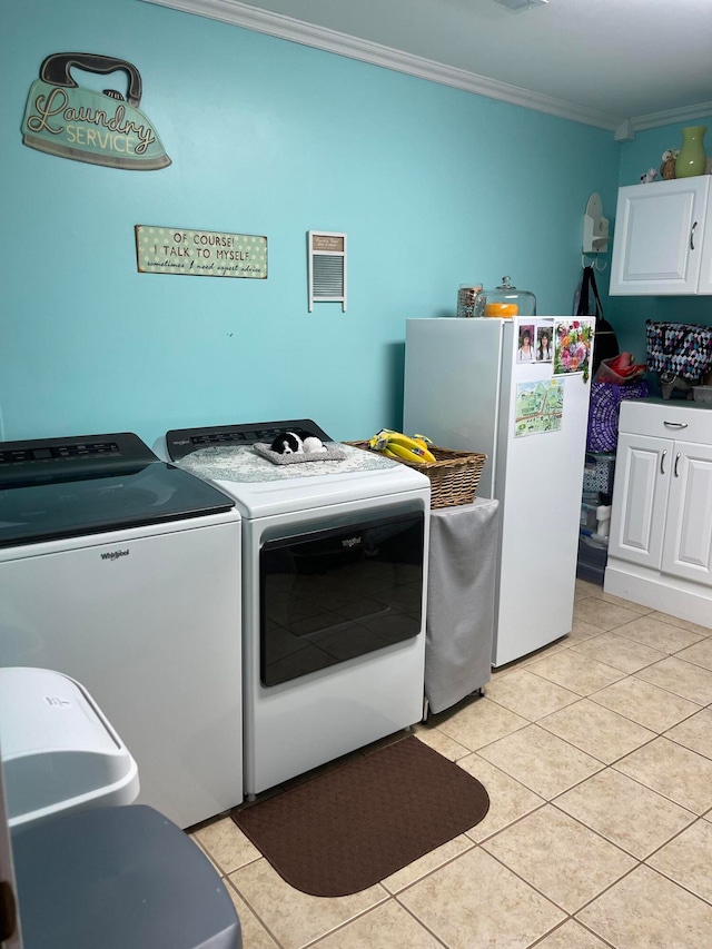 clothes washing area with crown molding, light tile patterned flooring, washing machine and dryer, and cabinets