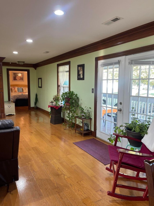 doorway to outside with ornamental molding, french doors, and light wood-type flooring