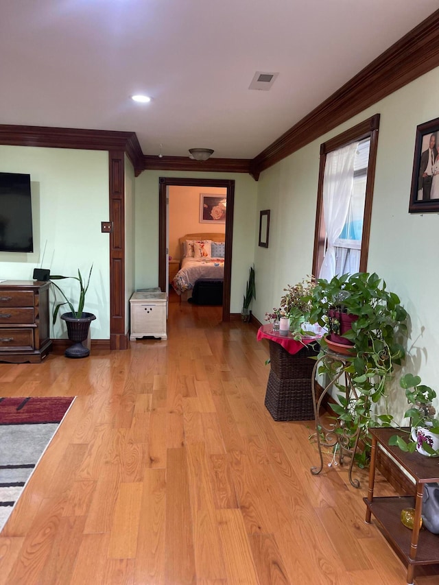 hallway with crown molding and light hardwood / wood-style flooring