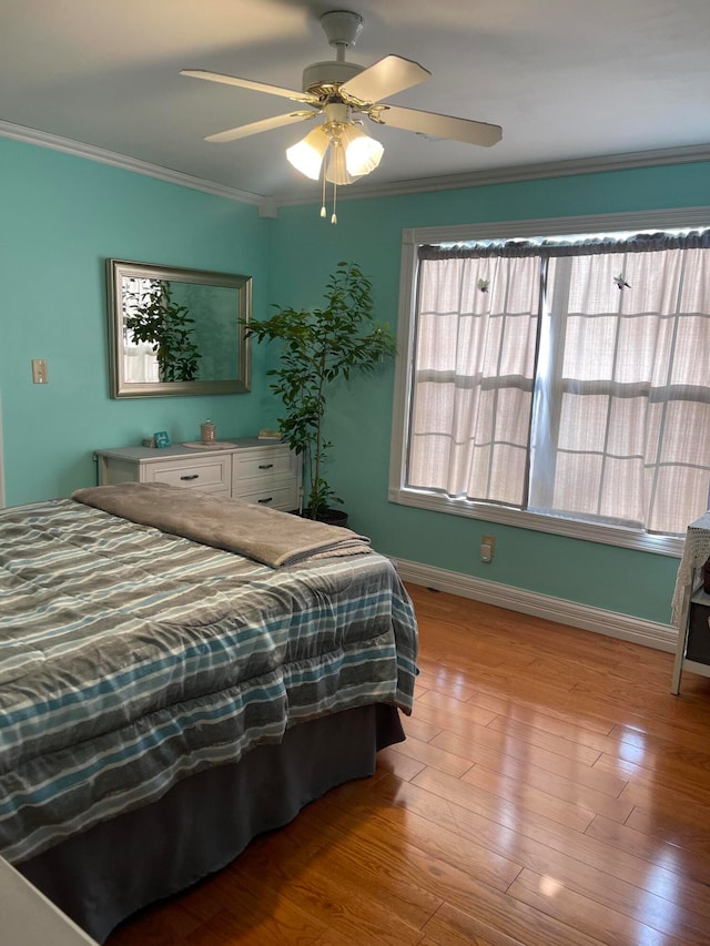 bedroom with ornamental molding, light wood-type flooring, and ceiling fan