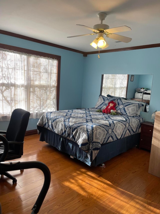 bedroom with ceiling fan, ornamental molding, and hardwood / wood-style floors