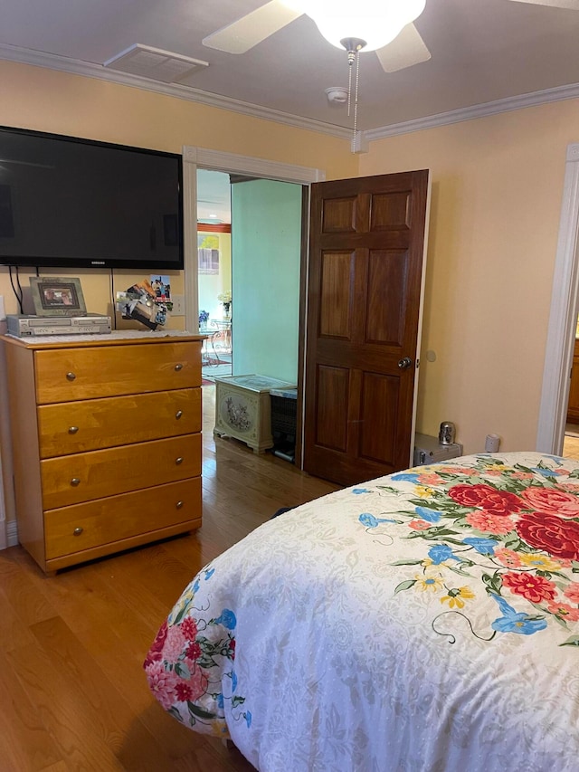 bedroom with ornamental molding, hardwood / wood-style flooring, and ceiling fan