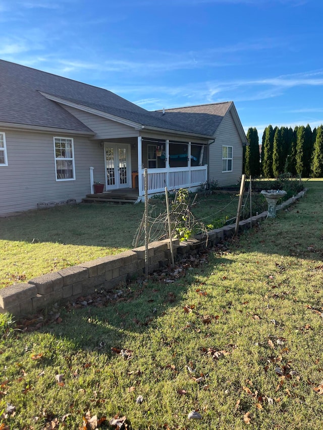 rear view of property with french doors and a yard