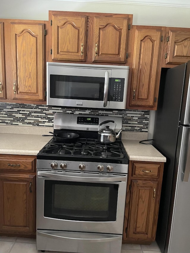 kitchen with tasteful backsplash, appliances with stainless steel finishes, and light tile patterned floors