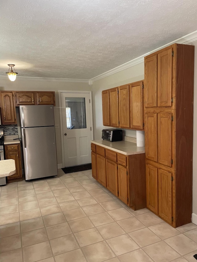 kitchen with backsplash, ornamental molding, stainless steel refrigerator, and a textured ceiling