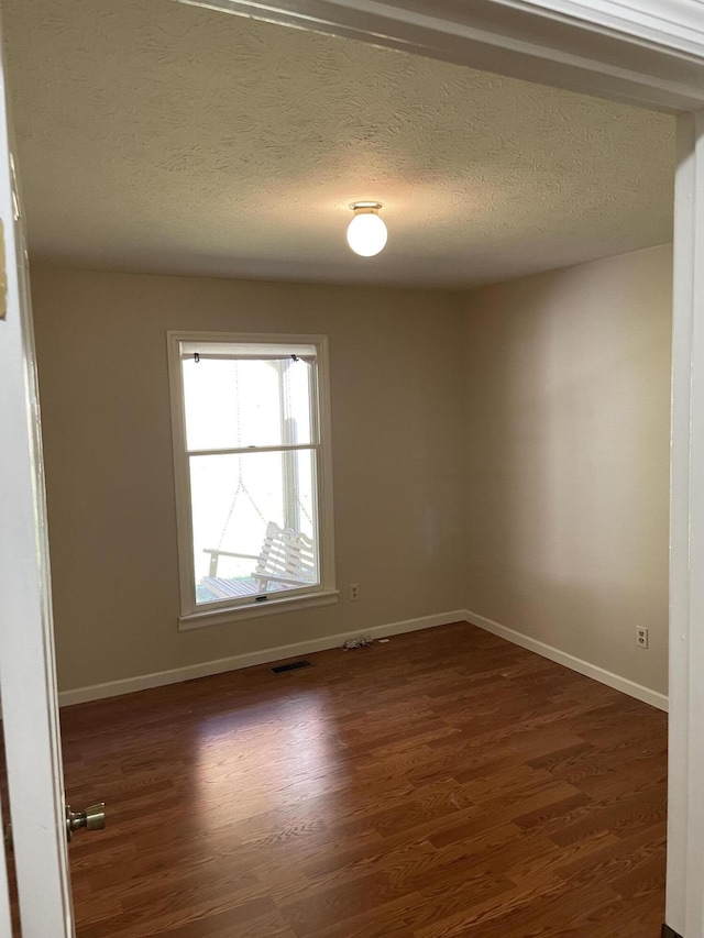 empty room featuring dark hardwood / wood-style flooring and a textured ceiling