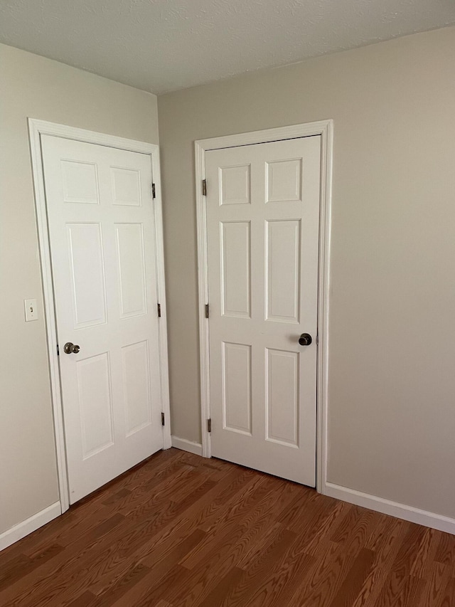 unfurnished bedroom with dark hardwood / wood-style flooring and a closet