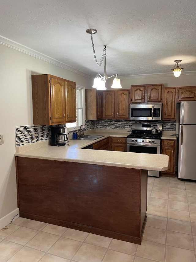 kitchen featuring pendant lighting, sink, appliances with stainless steel finishes, ornamental molding, and kitchen peninsula