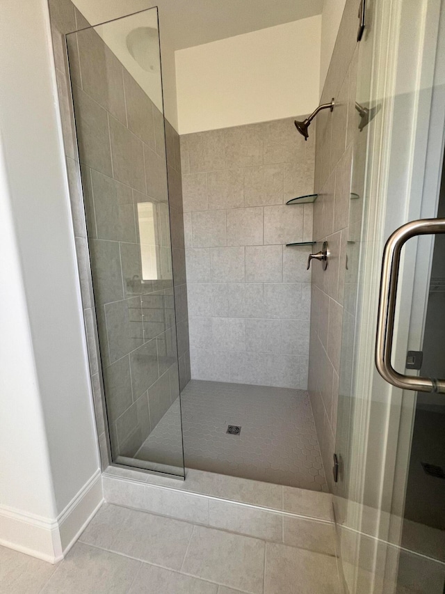 bathroom with a shower with door and tile patterned floors