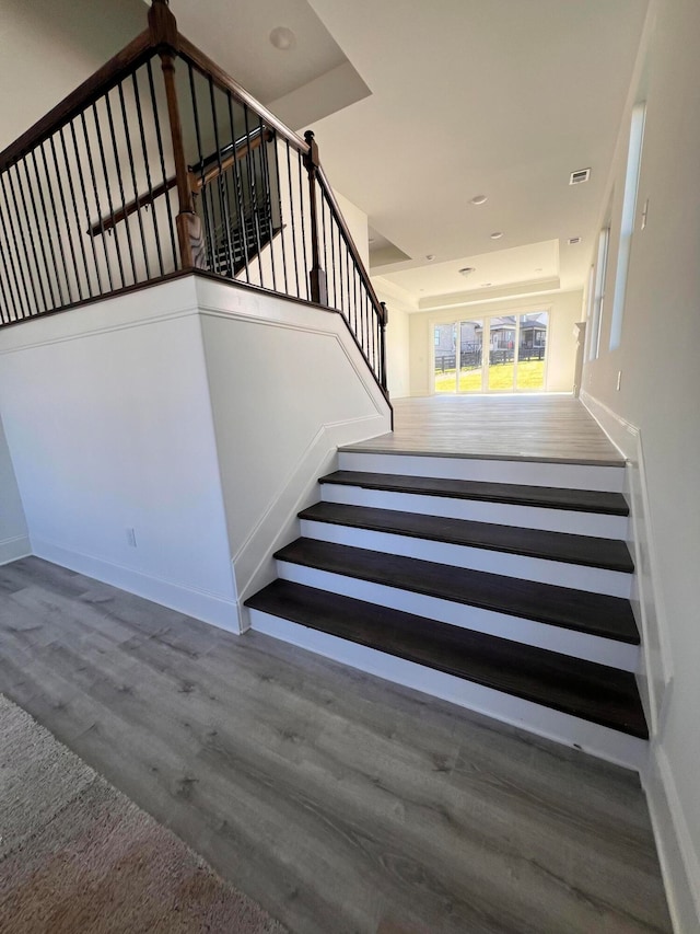 stairs featuring hardwood / wood-style floors and a raised ceiling