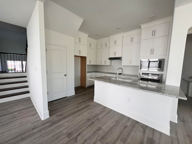 kitchen featuring white cabinets, appliances with stainless steel finishes, wood-type flooring, stone counters, and sink