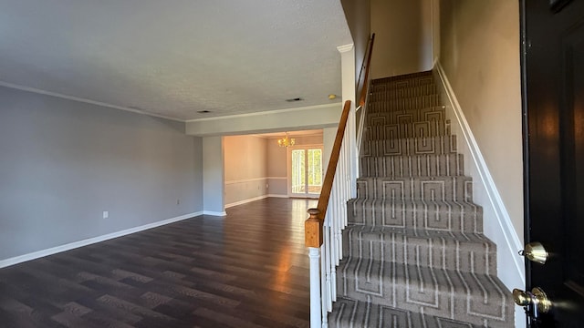 staircase with ornamental molding, an inviting chandelier, hardwood / wood-style floors, and a textured ceiling