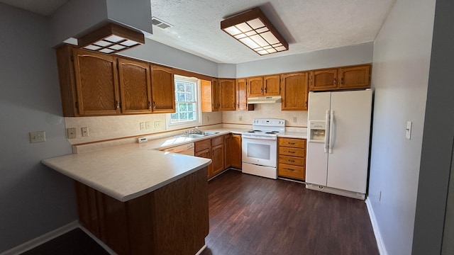 kitchen featuring white appliances, sink, a textured ceiling, kitchen peninsula, and dark wood-type flooring