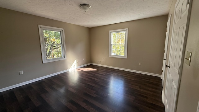 spare room featuring dark wood-type flooring and a textured ceiling