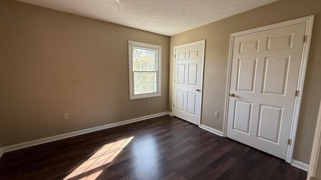 unfurnished bedroom featuring a textured ceiling and dark hardwood / wood-style flooring