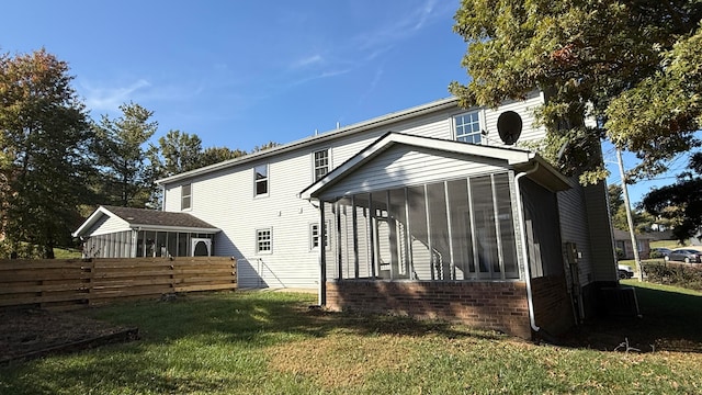 rear view of house with a yard and a sunroom