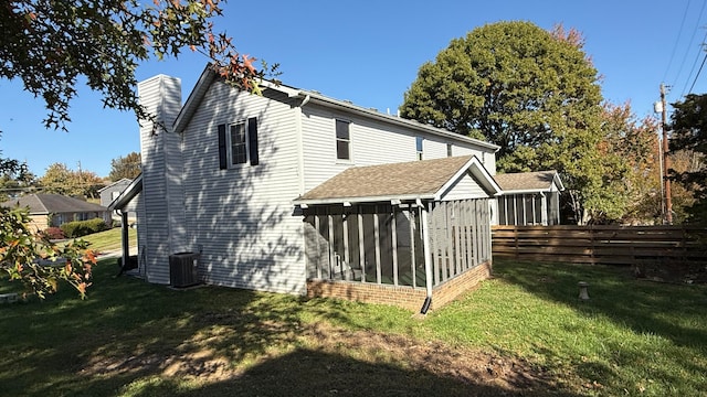 back of property featuring a sunroom, a lawn, and central AC unit