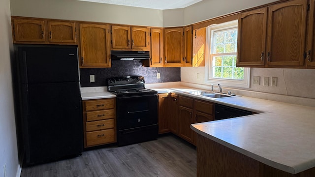 kitchen featuring black appliances, sink, dark hardwood / wood-style flooring, kitchen peninsula, and decorative backsplash