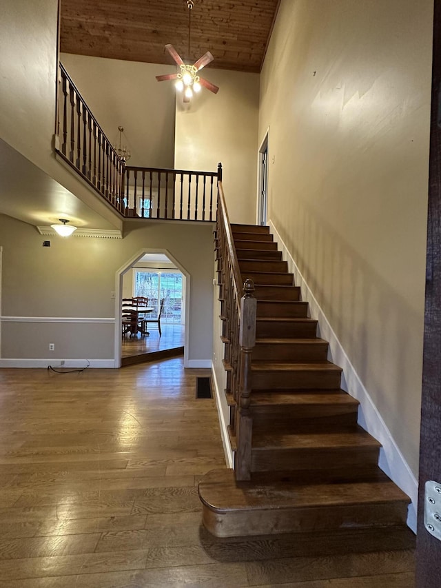 staircase featuring hardwood / wood-style flooring, ceiling fan, wooden ceiling, and a high ceiling