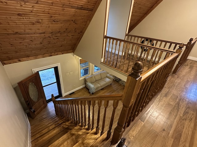 staircase with wood-type flooring, wood ceiling, and high vaulted ceiling