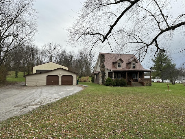 view of front facade with an outbuilding, covered porch, a front yard, and a garage