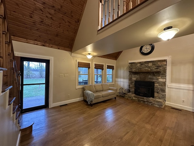 unfurnished living room featuring a stone fireplace, dark hardwood / wood-style flooring, high vaulted ceiling, and wood ceiling