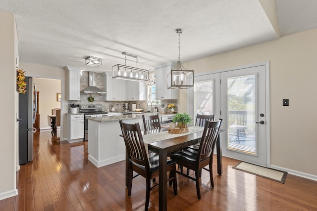 dining area with dark wood-type flooring, a textured ceiling, and a healthy amount of sunlight